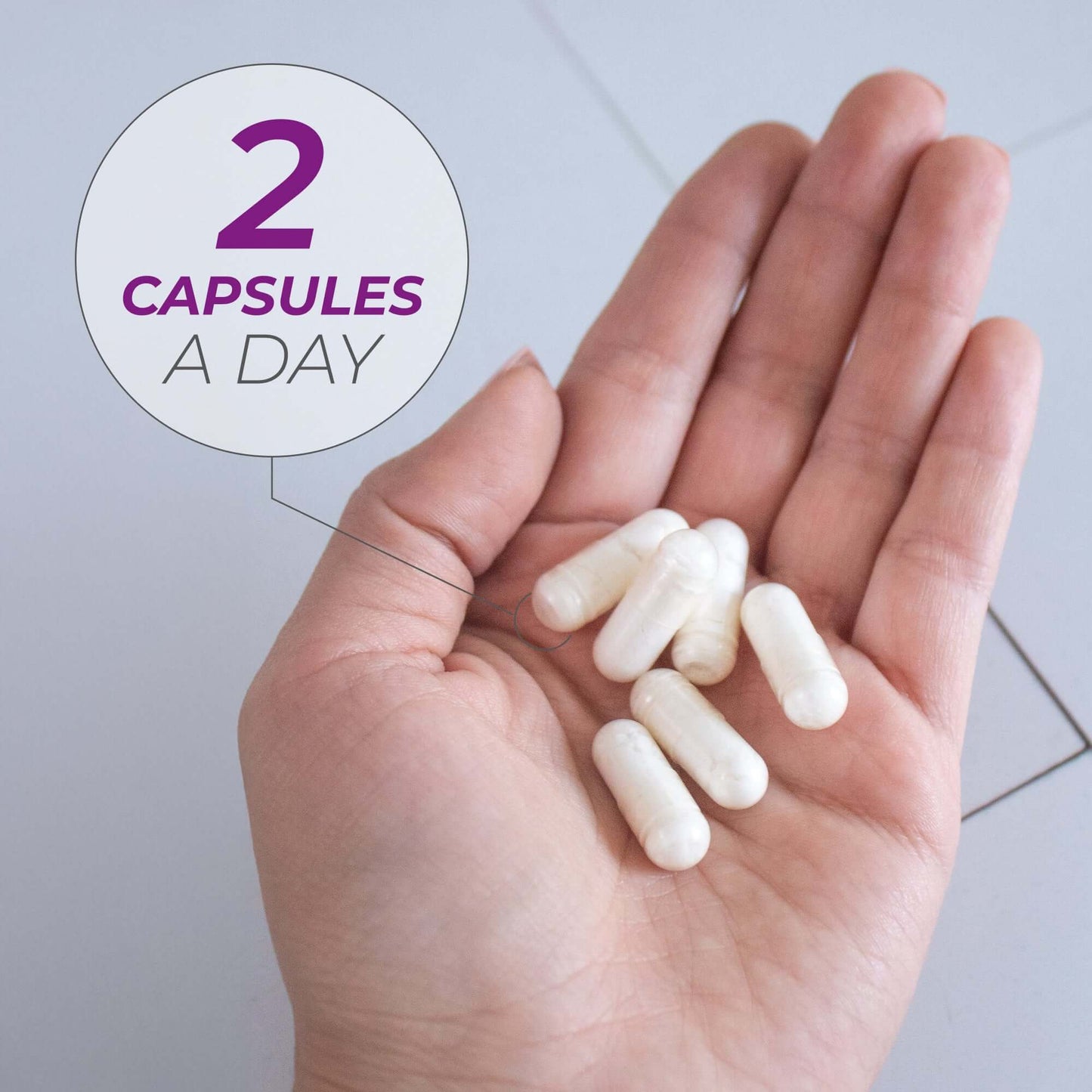 Hand holding two NMN + Resveratrol capsules for daily supplementation.